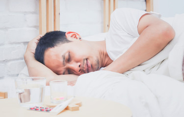 Obraz na płótnie Canvas Asian man sick and sleep on bed in bedroom