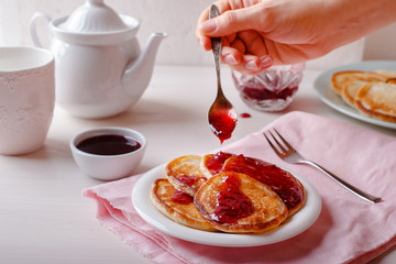 Traditional Russian Oladyi or pancakes with raspberry jam. Sweet breakfast or dessert concept