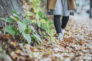 落ち葉の上を歩く女性の足元