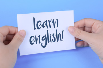 Woman's hand holding card with "learn english" writting in it