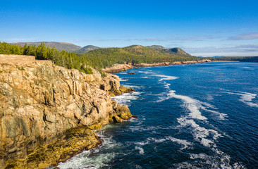 Aerial view of Acadia shore in Maine on a sunny morning with waves crashing on rocky cliffs