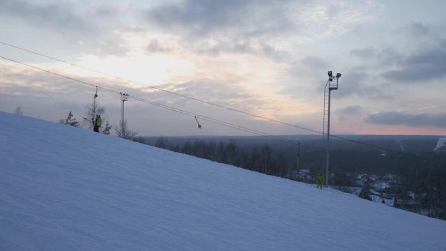 Skiers and snowboarders climb the hill on the hill in the ski resort. 4K