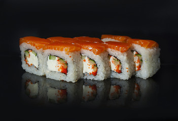 Japanese rolls are served on a black background with reflection.