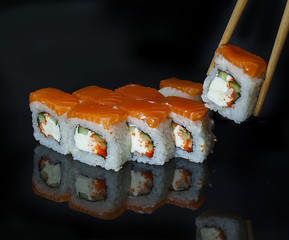 Rolls on black background with reflection. One roll is raised with a stick.