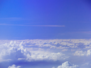 Naklejka premium Sea of clouds as seen from an airplane with horizon, deep blue sky and a white horizontal track of flight