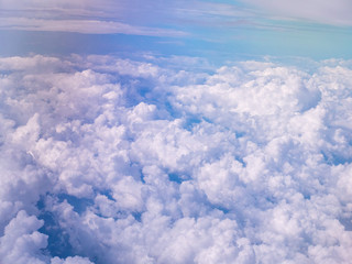 A sea of white fluffy clouds drifting as seen from a plane above with an area of empty  blue sky