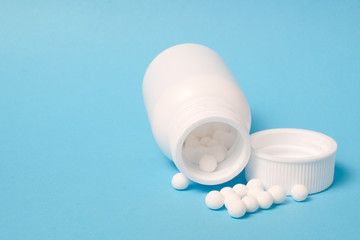 White pills and bottle on blue background