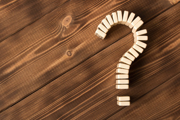 Domino question mark on wooden table. Domino principle.Empty text space.