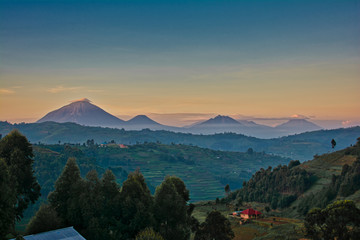 Fototapeta na wymiar Uganda volcanoes with morning clouds and layered colored sky
