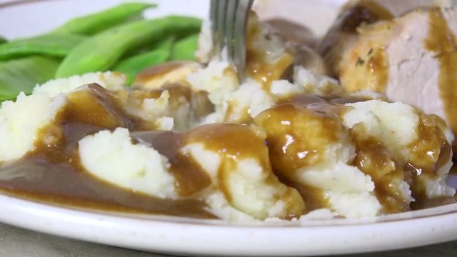 Taking a forkful of mashed potatoes and gravy, close up, slow motion