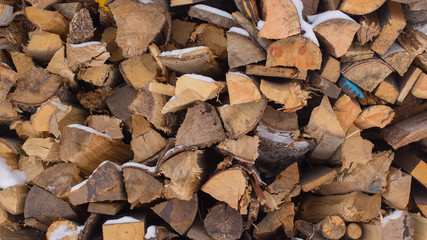 Close-up stacked chopped firewood partly with snow