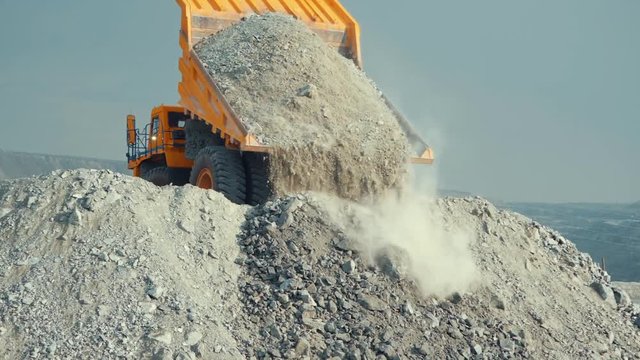 Mining loader unloads limestone ore or rock. View from the back.