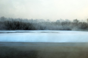 Winter landscape. The ice on the river. The mist over the water. Low air temperature.