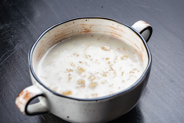 Morning Breakfast, oatmeal on milk with butter in white plate on dark background