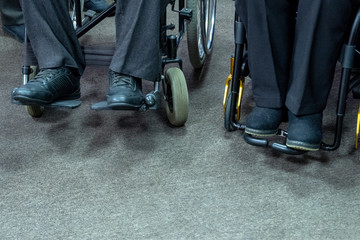 Obraz premium Two disabled people sit in wheelchairs. Close-up of legs. Copyspace.