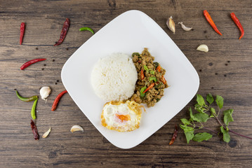 Spicy Thai basil with Crispy Chicken and Egg (Pad Krapow Gai) on table . it is a very delicious Thai food. Rice topped with stir-fried pork and basil leaves . street food in Thailand.