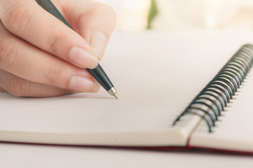 Woman hand with pen writing on notebook. Blank copy space.