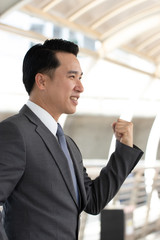 Fototapeta premium Asian businessman announce victory after successful investment project. He stands a handful of achievements. Soft focus and blur. Portrait handsome people.