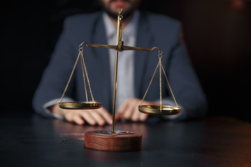 justice and law concept.Male lawyer in the office with brass scale on wooden table,reflected view