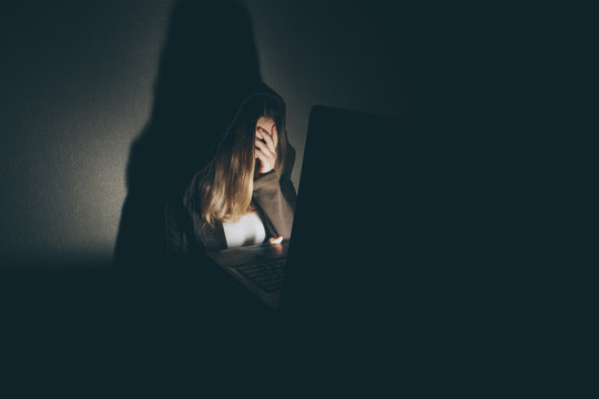 Teen girl excessively sitting at the computer laptop at home. he is a victim of online bullying Stalker social networks.Too much work sleepy stressed young woman sitting