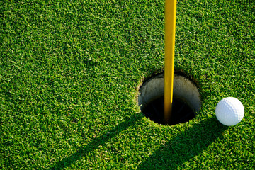 Golf ball on the edge of hole on the green grass