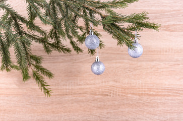 silver balls on spruce branch on wooden background