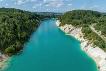 Abandoned mountain quarry. The mine workings are filled with water of a deep blue color. Aerial view