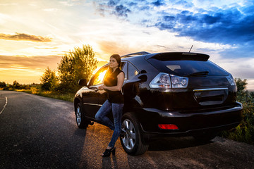 Fototapeta na wymiar Girl near big black car and sunset over the road