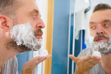 Guy shaving his beard in bathroom