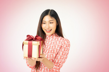 Photo of asian curious woman in red dress rejoicing her birthday or new year gift box. Young woman holding gift  box with red bow being excited and surprised  holiday present isolated white background