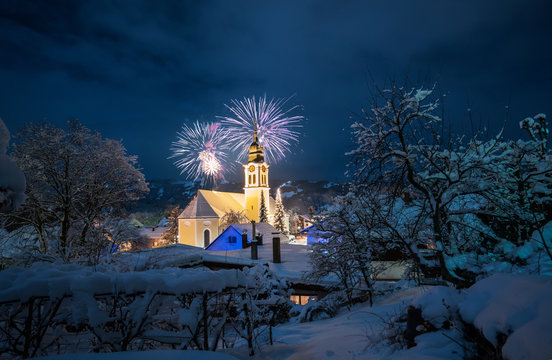 Church in snowy winter landscape with fireworks, celebrating the new year, Sonthofen Germany
