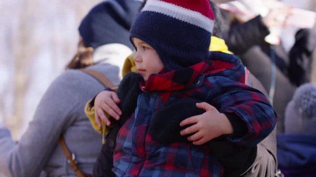Mother puts son on her lap for tractor ride at christmas tree farm