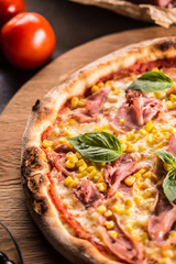 Italian pizza cardinale with ham prosciutto tomatoes corn and basil