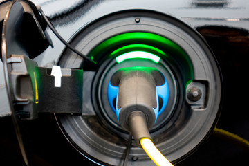 EV Car or Electric car at charging station with the power cable supply plugged. Eco-friendly alternative energy concept.