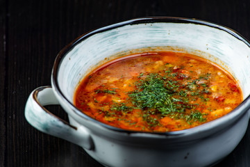 Vegetable soup with red beans, borscht, tomato soup, soup kharcho in a white plate on a black background