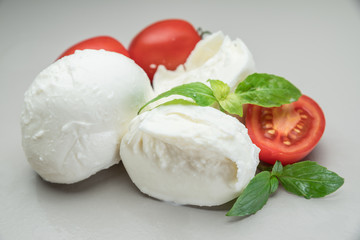Traditional Italian mozzarella cheese with herbs and tomatoes on gray background.