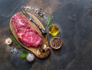 Raw  Rib eye steak or beef steak on the graphite board with herbs and spices.