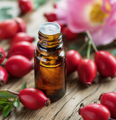 Rose-hips and rose hip seed oil on the wooden table.