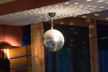 Silver mirror disco ball in the rays of the spotlights