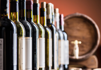 Wine bottles in row and oak wine keg. © volff