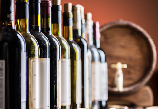 Wine bottles in row and oak wine keg.