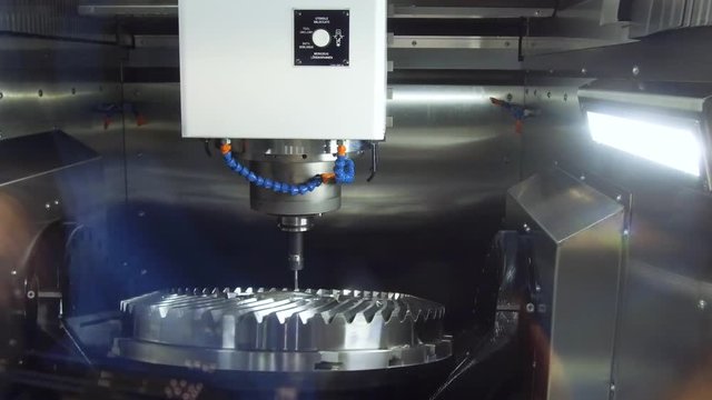 A modern CNC milling machine makes a large cogwheel.