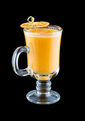 A hot drink with orange, almonds and spices. On dark background. Warming drink.