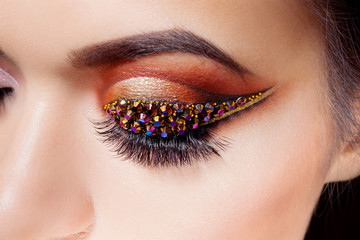 Amazing Bright eye makeup with a arrow with rhinestones. Brown and gold tones, colored eyeshadow