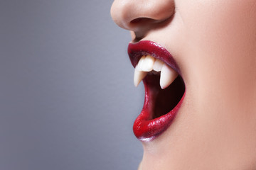 Sexy vampire. Women's lips with red lipstick. Screaming mouth with vampire fangs - obrazy, fototapety, plakaty