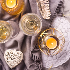 Two glasses of champagne on a gray plaid among gold and white Christmas decorations. Top view, flat lay
