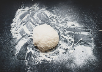 Baking background with dough and flour on dark table. 