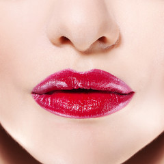 Women's lips with bright red lipstick, Rich color and glossy texture, used lip gloss.