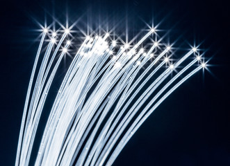 Bundle of optical fibers with lights in the ends. Blue background.