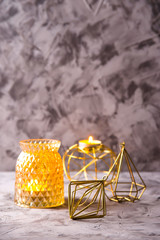 Golden Christmas decorations and candlesticks with burning candles on gray background. Festive minimalism. Copy space